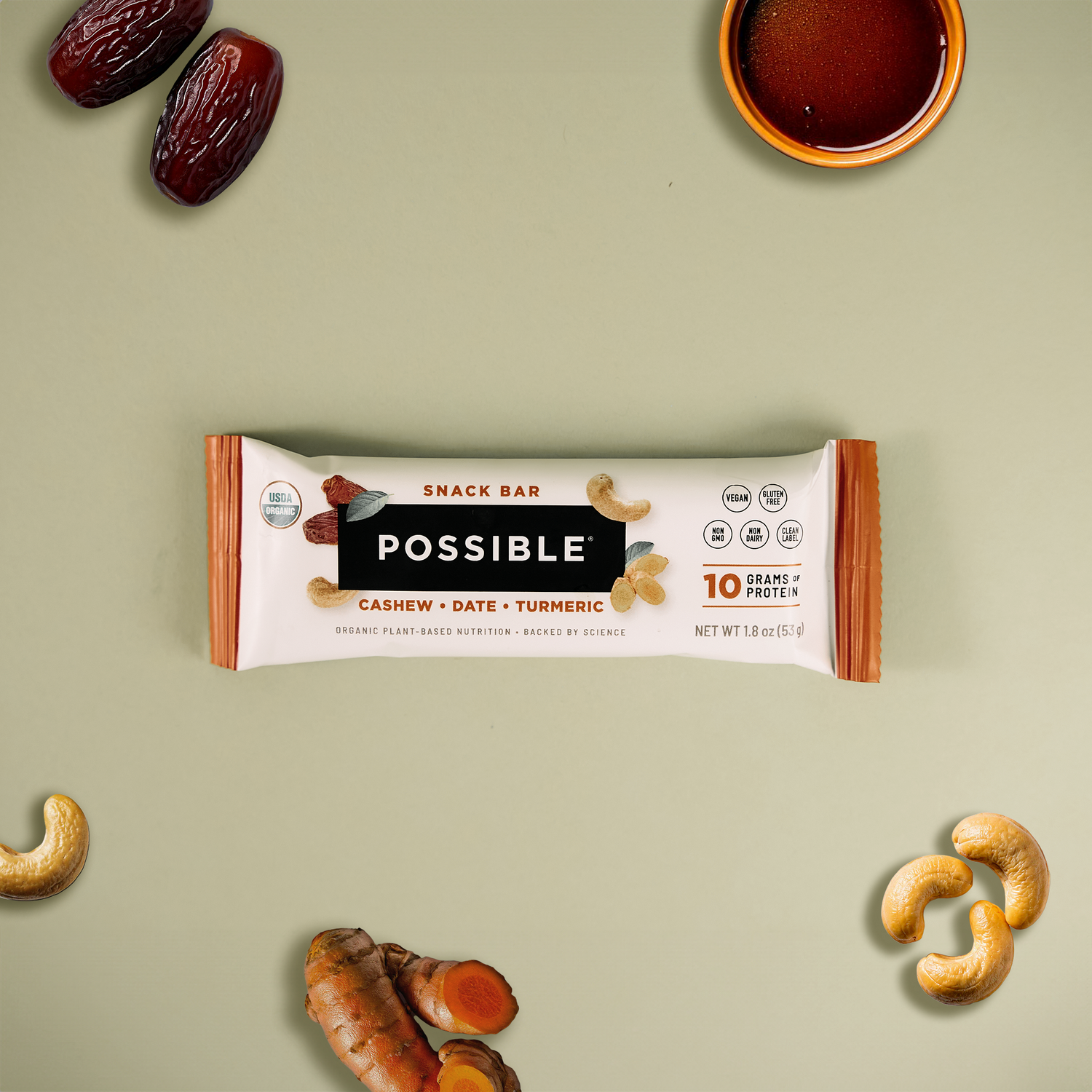 POSSIBLE Cashew Date Turmeric Snack Bar displayed with key ingredients including cashews, dates, turmeric, and a drizzle of syrup, showcasing whole food nutrition and plant-based protein.