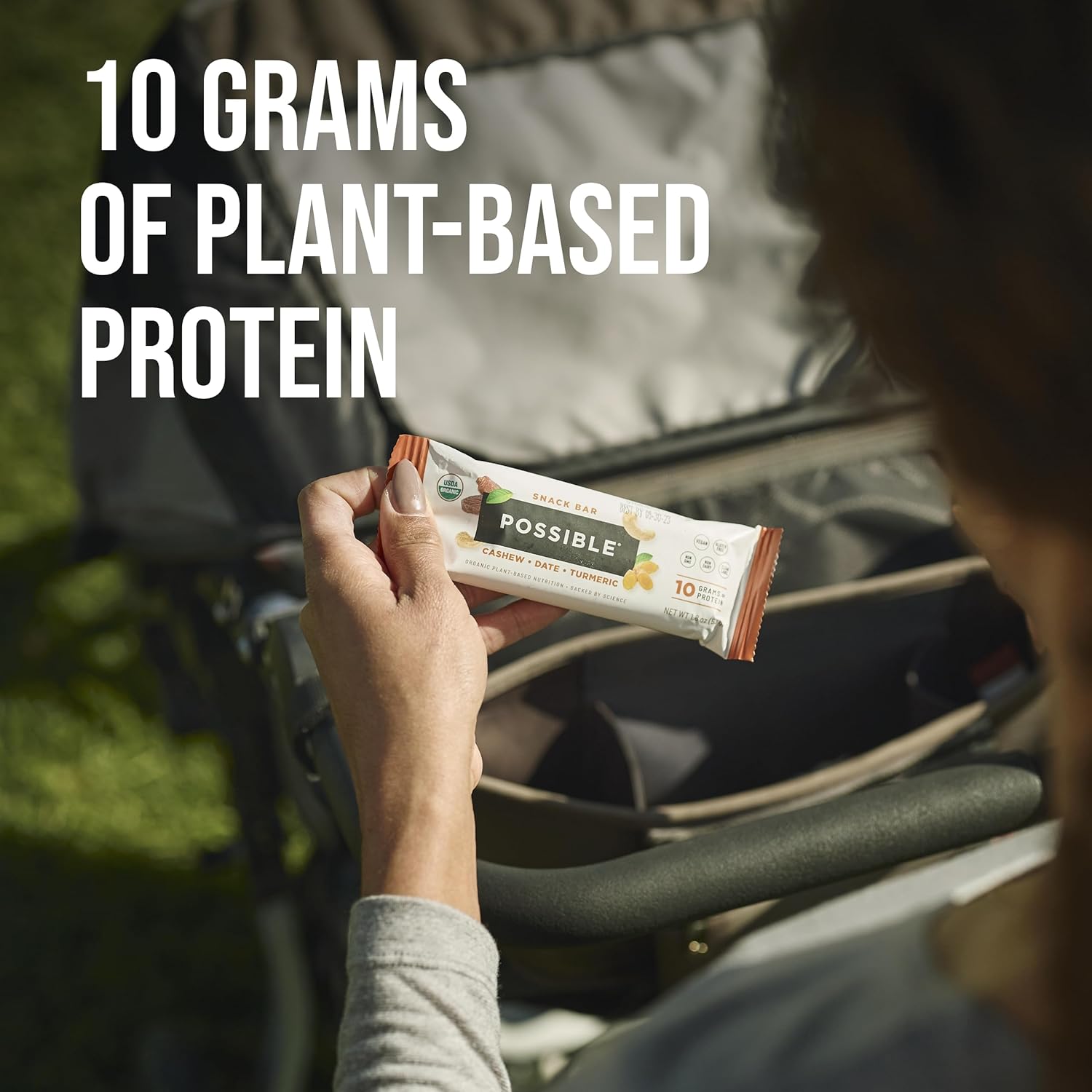 POSSIBLE Cashew Date Turmeric Snack Bar in hand, ideal for on-the-go snacking, providing 10g of plant-based protein for sustained energy and performance.